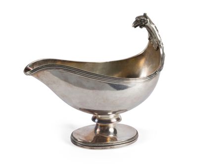 une saucière ancienne en métal argenté, posée sur un socle et surmontée d'un oiseau