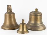 three antique brass bells on a white background