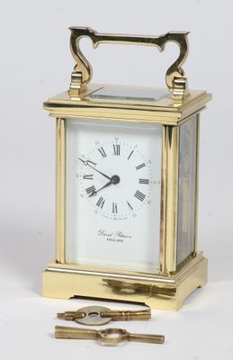 a small gold clock with a key in front of it