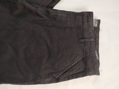 Le pantalon est noir et comporte une fermeture éclair sur le côté.