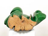 a wooden sculpture of a leaf on a white pedestal