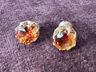 pair of orange crystal earrings on a purple cloth