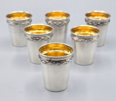 six verres à shot argentés aux bords dorés sur fond blanc