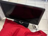 a red pillow on the floor next to a flat screen tv