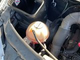 a car engine with its hood open and a gas can in the trunk