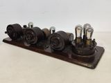 an old fashioned steam engine with four valves on a wooden stand