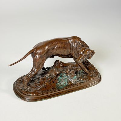 statue en bronze représentant un chien assis sur un rocher, tenant un oiseau dans la gueule