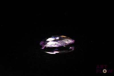 a close up of a purple and white diamond on a black surface