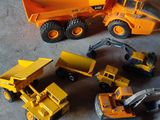 Plusieurs engins de chantier miniatures sont alignés sur le sol