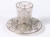 une tasse en verre et sa soucoupe posées sur une soucoupe