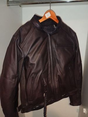 une veste en cuir marron suspendue à un cintre dans un placard