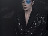 tableau représentant un homme en costume noir, le visage recouvert de peinture bleue