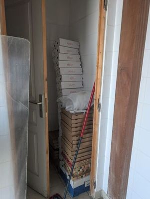 a mop that is sitting on the floor next to a stack of pizza boxes
