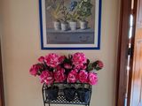 un vase avec des fleurs roses posé sur un socle dans une pièce
