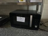 a microwave sitting on a counter with a note taped to it