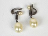 une paire de boucles d'oreilles en perles et diamants posées sur un fond blanc
