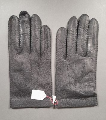 pair of black leather gloves with tags on them on a table