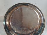 une assiette en argent posée sur une table, sur fond blanc