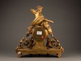 a gold clock with a statue on top of it