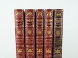six livres rouges sont alignés sur une surface blanche