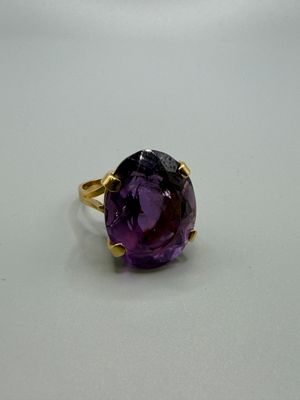 gros plan d'un anneau de pierre violette sur une surface blanche