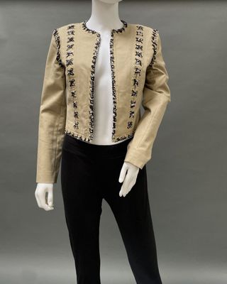 a mannequin wearing a beige jacket and black pants