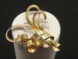 a gold bow brooch sitting on a white cup