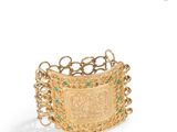 a close up of a gold bracelet with green stones on it