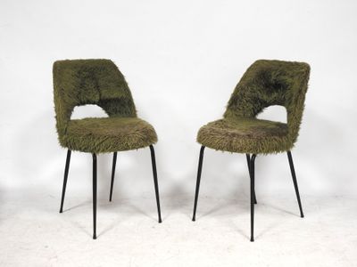 two green chairs with black legs and a white wall in the background