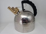 a silver tea kettle with a gold handle on a white table