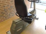 a stationary exercise bike in a gym room with a monitor on the wall