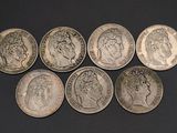 six different types of silver coins on a black surface