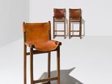 two brown leather chairs in a white room with a white wall