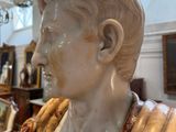 a marble bust of a man in a room with a chandelier in the background