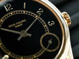 a close up of a watch with a black face