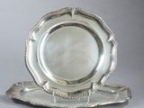 une assiette en argent posée sur un plateau en argent, sur une table