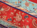 a red, blue, and green oriental rug hanging from a tree