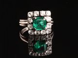 une bague en émeraude et diamant sur une surface noire