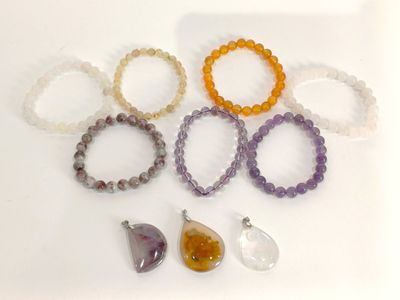 sept bracelets et un pendentif posés sur une surface blanche