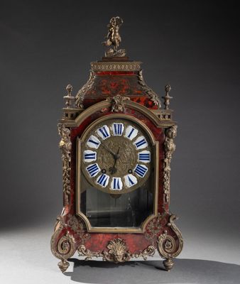 une horloge rouge et dorée ornée de chiffres romains bleus