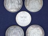 four silver coins of different sizes and shapes on a blue background