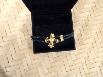 a black box with a gold fleur de lis brooch on it