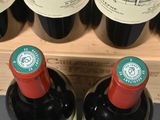 two bottles of wine sitting on a shelf next to each other