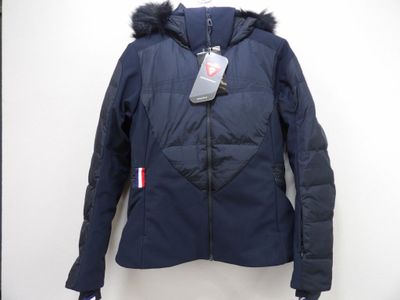 La veste est bleue et possède une capuche bordée de fourrure.