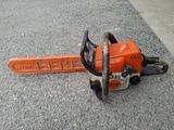 an orange chainsaw sitting on the ground next to a sidewalk