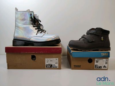 une paire de bottes noires et argentées posées sur des cartons
