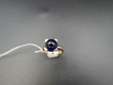 une bague sertie d'une pierre bleue, posée sur une table