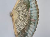 an old fan hanging on a wall with a painting on it