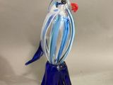 un oiseau en verre posé sur un vase bleu
