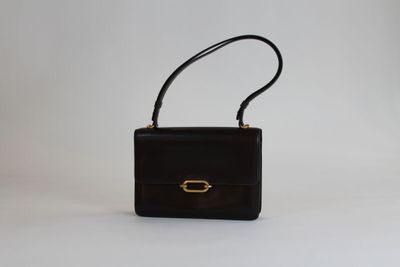 un sac à main noir avec un fermoir doré sur fond blanc